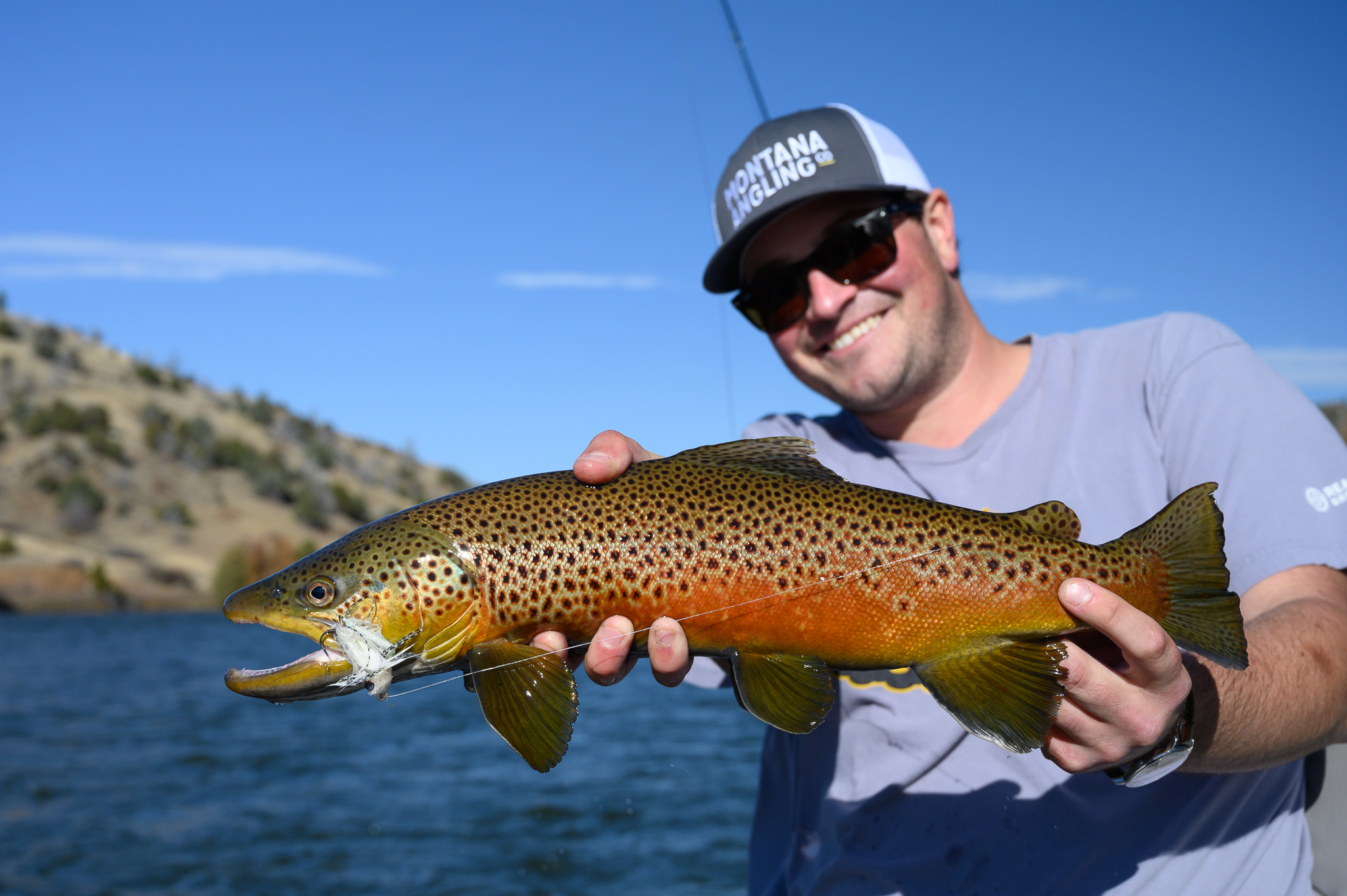 Angler with a brown trout on a fall fly fishing trip in Montana